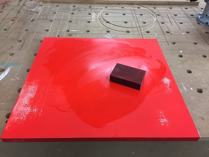 Rödmålad kökslucka i MDF med slipblock ovanpå, i en verkstadsmiljö.