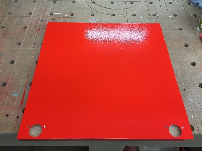 Röd målad MDF-skåpsfront med frästa fingergrepp och synliga bearbetningssteg.