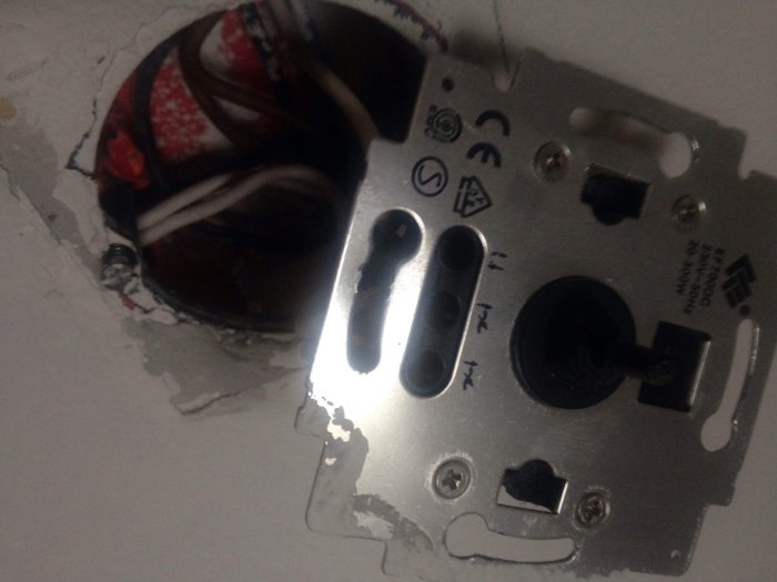 Gammal trappkopplad dimmer med tre inkopplade vita sladdar, otydlig märkning, monterad i vägg.