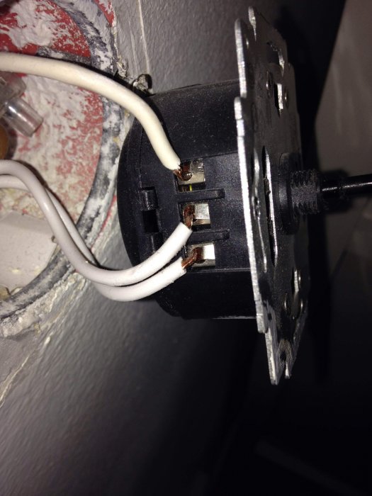Trådbundet väggmonterad ljusdämpare (dimmer) med tre vita kablar anslutna.