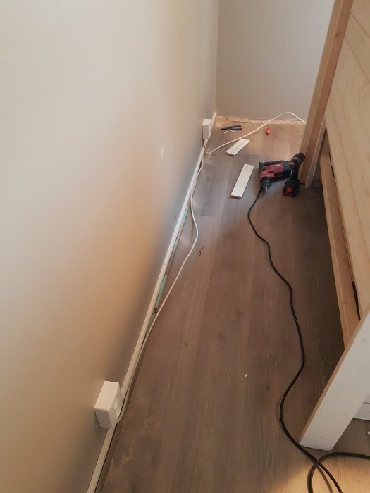 Elektrisk kabelinstallation längs med golvsockel i ett rum under renovering.