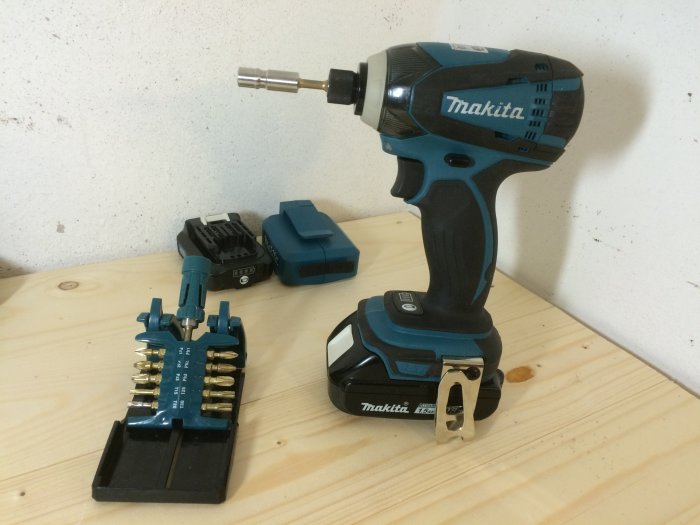 Makita slagskruvdragare och bitsats på arbetsbänk, inklusive batteri och laddare.