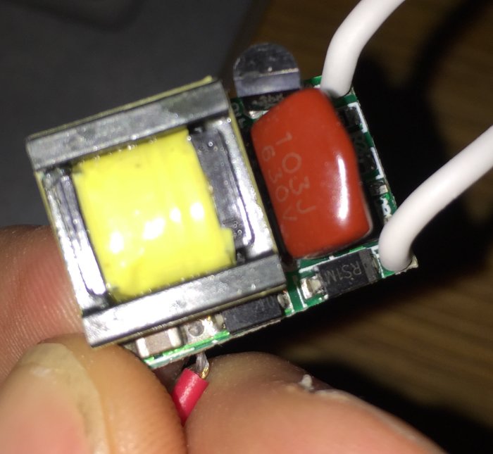 Närbild av en elektronisk komponent med en gul diod och en röd kondensator.
