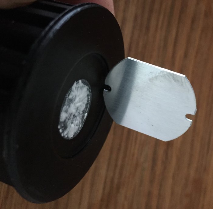Närbild på en hand som håller en svart rund elektronisk komponent med en osynlig diod.