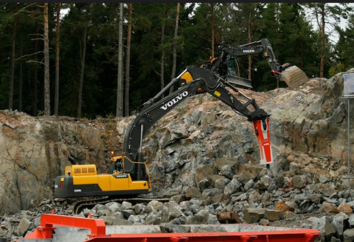 En grävmaskin av märket Volvo används för att bryta och lyfta sten i en stenbrottlig terräng.