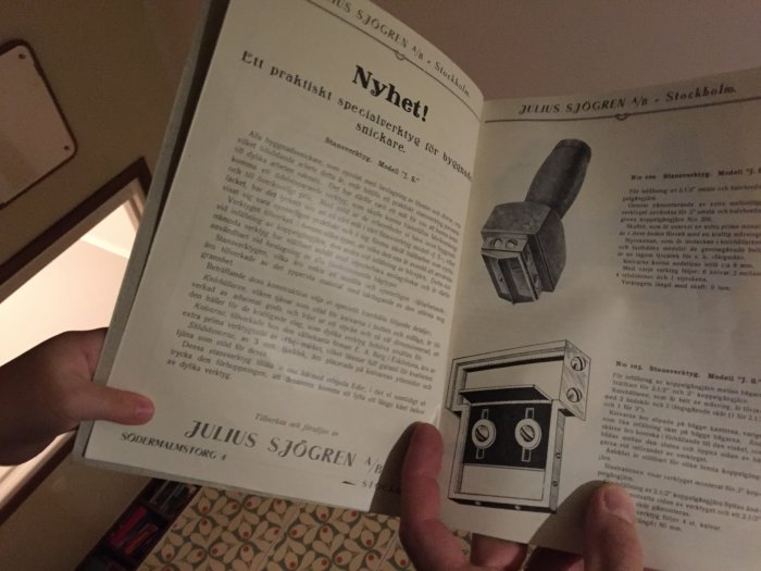 Händer som håller upp en öppen verktygskatalog från 1929 med text och illustrationer av verktyg.