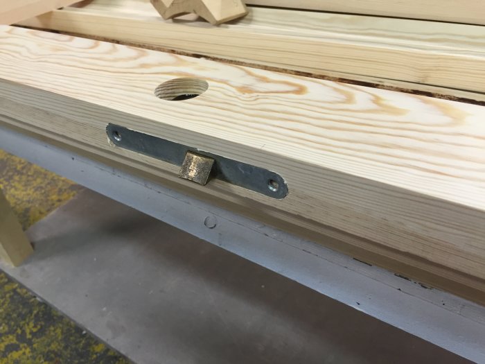 Närbild av en träkonstruktion med ett metallbeslag och falsning som del av en dörr till matkällare.