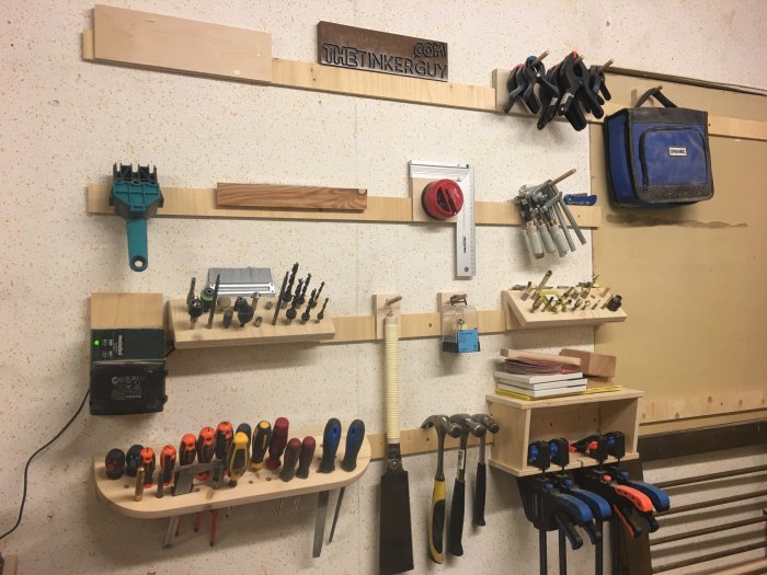 Väggmonterad organiseringslösning i verkstad med mejslar och verktyg ordnade på hyllor och hållare.