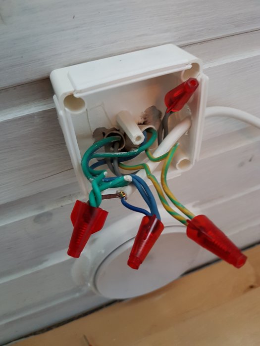 Öppen kopplingsdosa med färgkodade elkablar och skarvhylsor, använd för att diskutera elinstallation i hemmiljö.