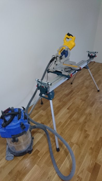 En Dewalt såg med förändrad Bosch-klinga på ett sågbord nära en vägg i ett rum med parkettgolv.