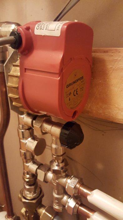 Grundfos cirkulationspump installerad på kopparledningar och ventiler i ett värmesystem.