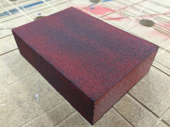 Slipblock i rött efter andra strykningen av vattenbaserad lackfärg, något matt yta.