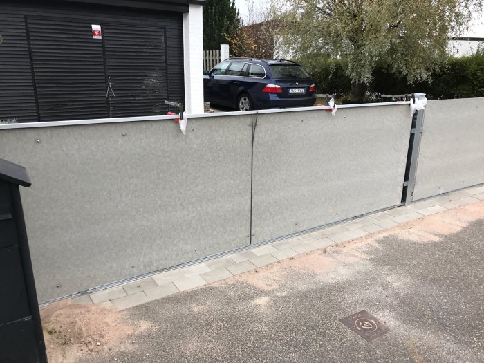 Installation av aluminiumlister med LED-profil längs en grå betongvägg, bredvid en parkerad bil.