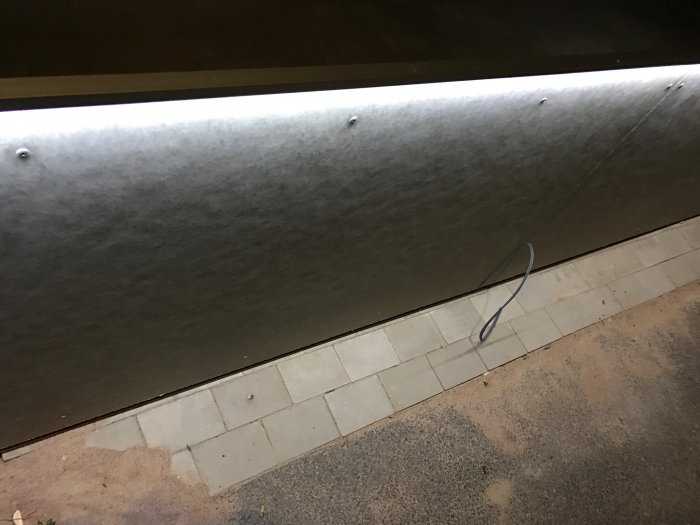 Montering av en aluminiumlist med inbyggd ledprofil längs en vit kaklad vägg, belysningen ej fullt synlig.