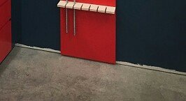 Röd köksinredning med öppet skåp utan sockel längs golvet, mörkgrått golv och vägg.