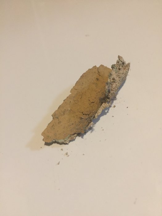 Flagande färgprover från en källarvägg som visar gammal färg som lossnat och behöver ommålning.