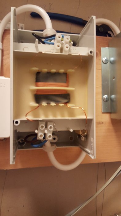 Transformator öppnad visar interna komponenter och platsen för en 3,15 A-säkring i det nedre högra hörnet.