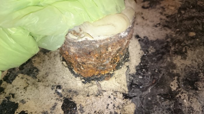 Rostigt avloppsrör vid golvet som skyddats med plast medan det omgivande golvet är uppbilat.