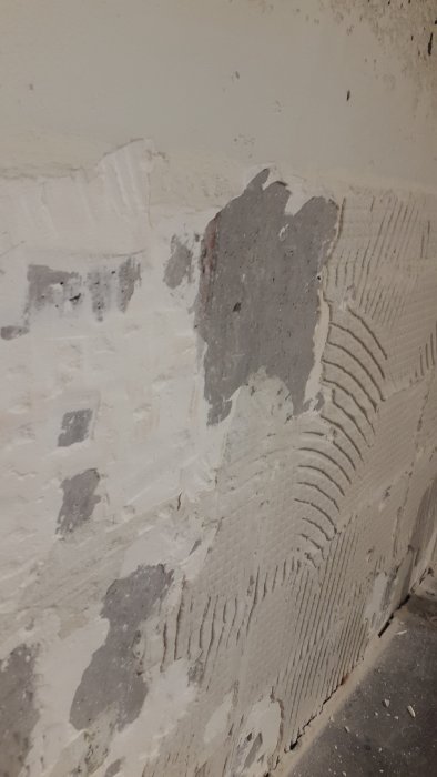 Betongvägg med ojämnt fix efter borttaget kakel under renovering av kök.