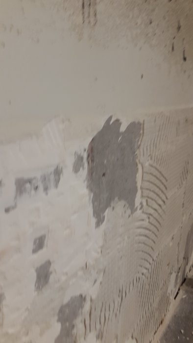 Betongvägg med ojämnt kvarvarande fix efter borttaget kakel under köksrenovering.