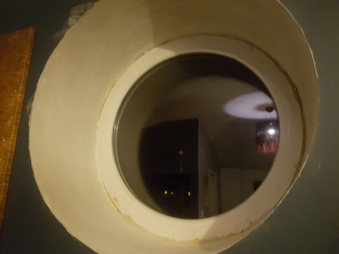 Runt fönster med spacklad och slipad insida nära kanten, inte helt jämnt, redo för ytterligare spackling.