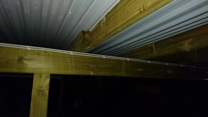 Vy under altan med plasttak monterat mellan träreglarna där vatten läcker igenom skarvarna.