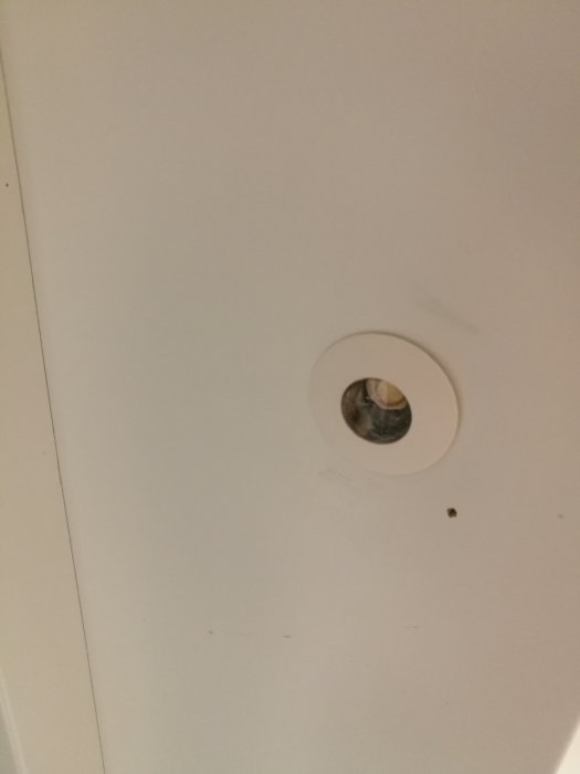 Spotlight i taket med vit omgivning, synliga nummer och tecken på åldring.