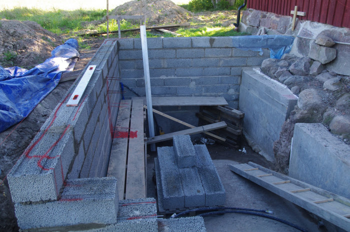 Grundkonstruktion med lecablock över en betongsockel, armering markerad, vid husbygge.