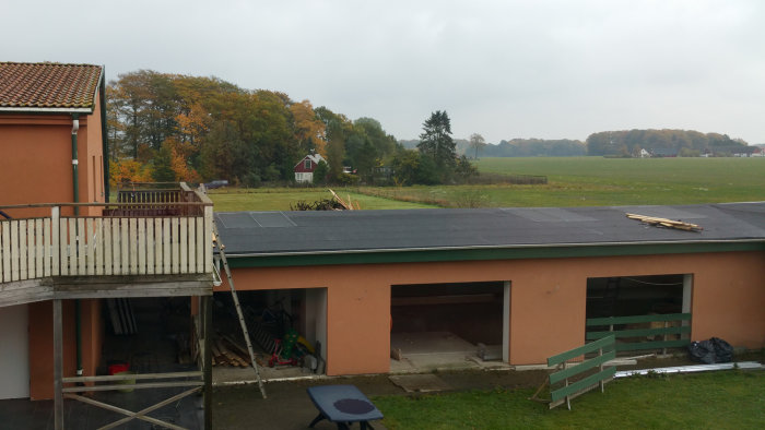 En bakgård med ett hus som har solpaneler på taket, en delvis rivet balkong med utsikt över en öppen landsbygd.