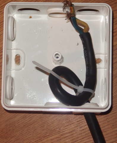 Elkabel med löstagbar isolering och ledare i en vit elektrisk dosa, improviserad dragavlastning med buntband.