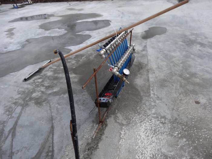 Ett radonventilationssystem med öppna ventiler och mätinstrument på en betongyta med vattensamlingar.