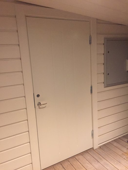 Nyinstallerad dörr i ett renoverat förråd som konverteras till kontor, med träväggar och golv.