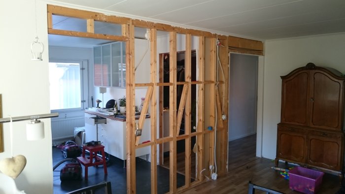 Bild av en pågående renovering av en rumdelande trävägg med markerad framtida öppning mellan de röda strecken.