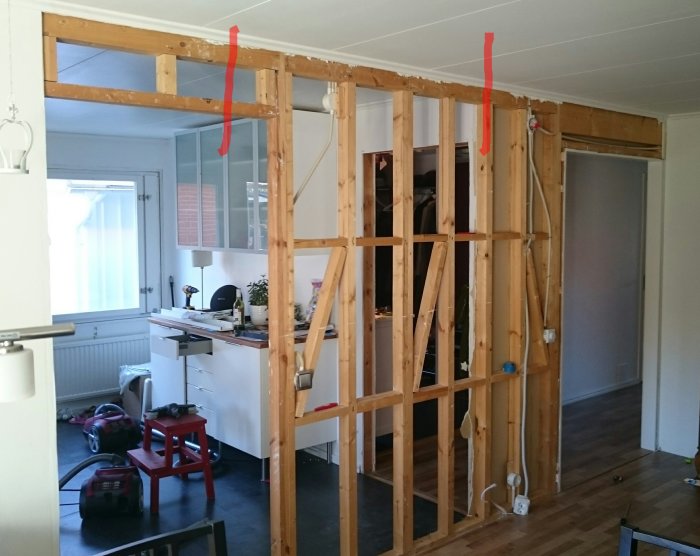 Bärande trävägg i renoveringsfas med markerad öppning mellan röda linjer i ett hus.