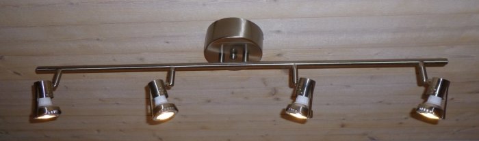Taklampa med fyra LED-spottar monterade på metallstång i en tvättstuga.