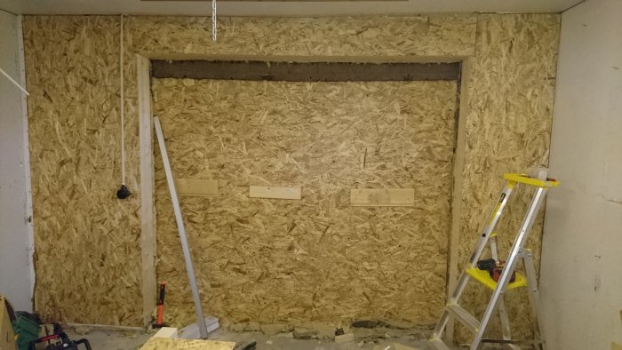 Renoverat garage med OSB-väggbeklädnad, utsparat för port installation och byggstege.