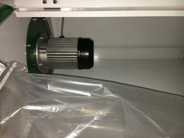 Maskinkomponent i en "plåtlåda", täckt av plast, relaterat till spånsug och filterunderhåll.
