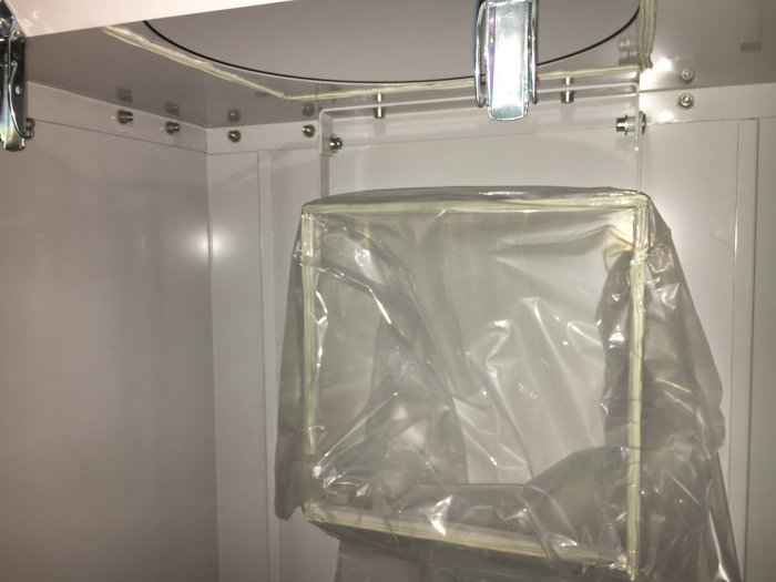 Industriellt filterhölje täckt av plast inne i en metallkonstruktion med synliga ledningar.