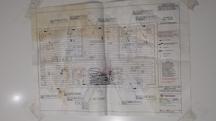 Sliten ritning med uppmärkta värmeslingor för golvvärme i olika rum, inga synliga modifieringar på baksidan.
