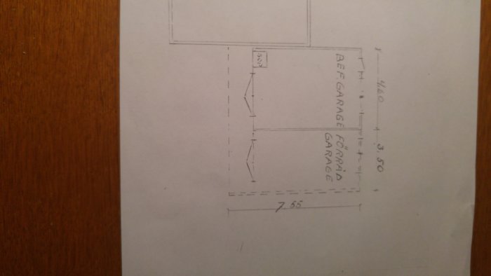 Handritad skiss av garage med måttangivelser på ett pappersark.