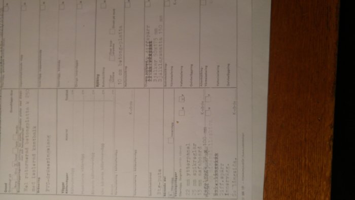 Roterad bild av ett ifyllt formulär på ett träbord, texten är oskarp och svårläst.