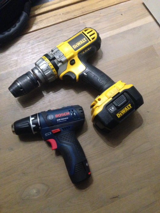 Två borrskruvdragare på ett trägolv: en gul och svart DeWalt och en mindre blå Bosch.