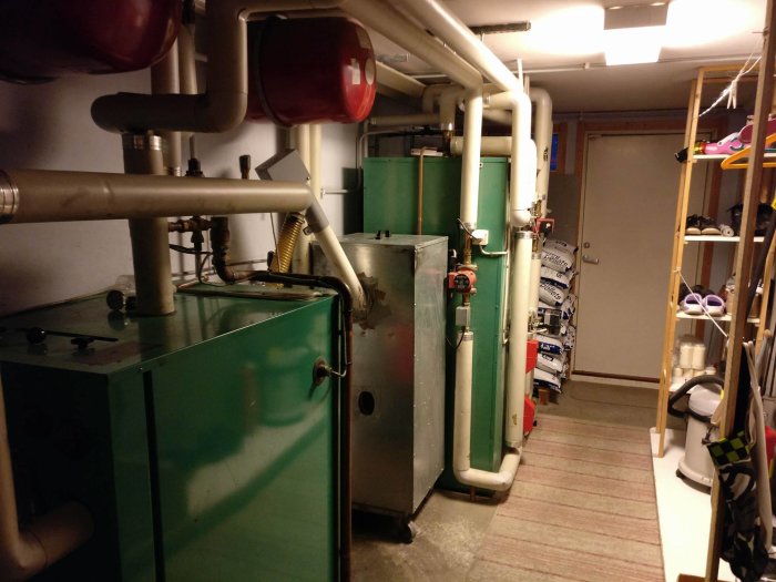 Värmesystem i källare med gröna tankar och rör samt vattenberedare.