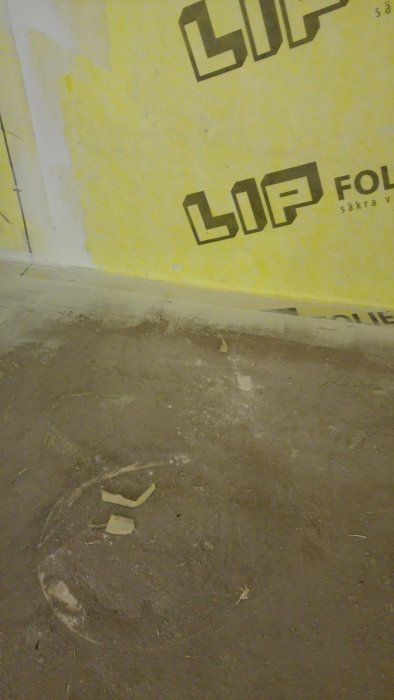 Hörnet där ett golv möter en vägg med LIP tätskikt, överlappning och spackel synligt på golvet.