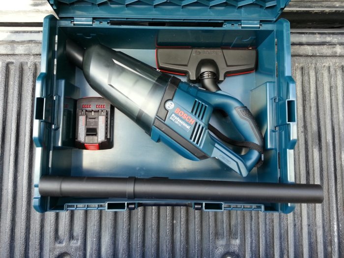 Bosch trådlös dammsugare och batteri i en blå verktygslåda.