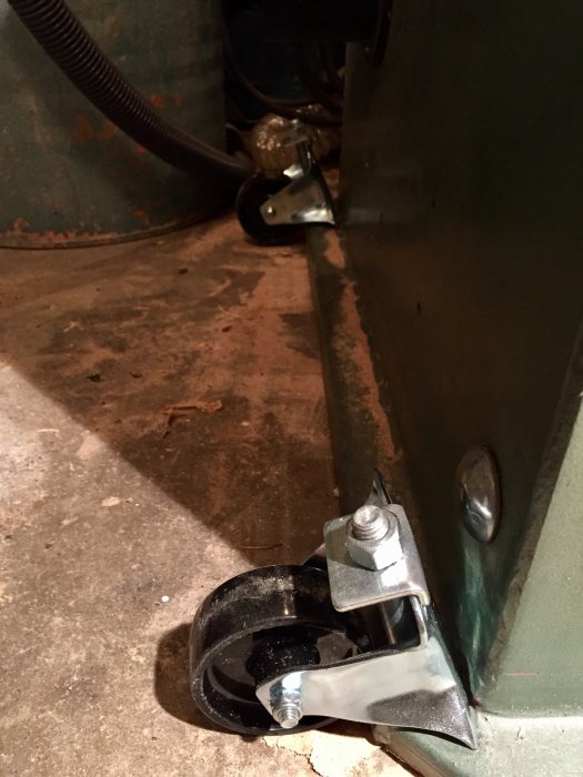 Monterat transporthjul med bockad fyrkantsbricka på en tung maskin för att underlätta förflyttning.