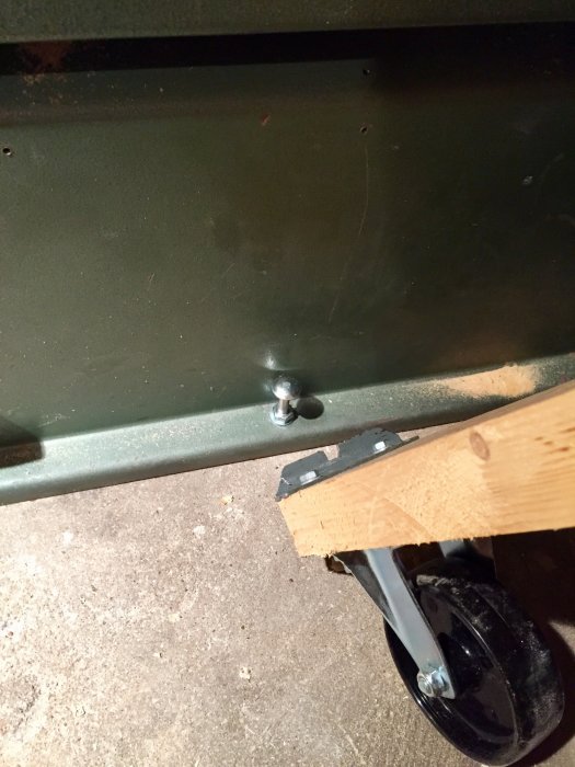 Monterat transporthjul på verktygsmaskinens ben med en bockad fyrkantsbricka och bult.