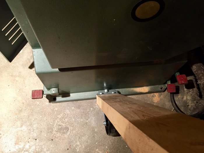 Sågmaskin på verkstadsbetonggolv med monterade transporthjul och bockad fyrkantsbricka.