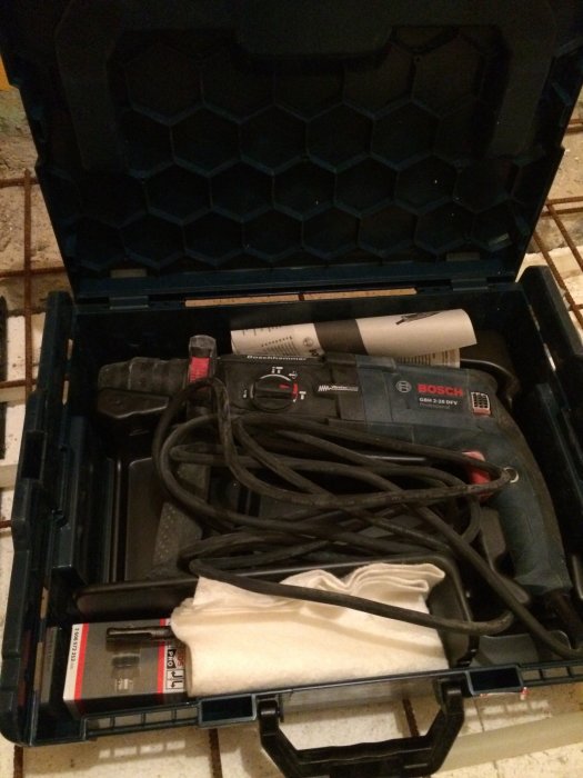 Ny Bosch borrhammare GBH 2-28 med sladd i en öppen verktygslåda tillsammans med tillbehör.