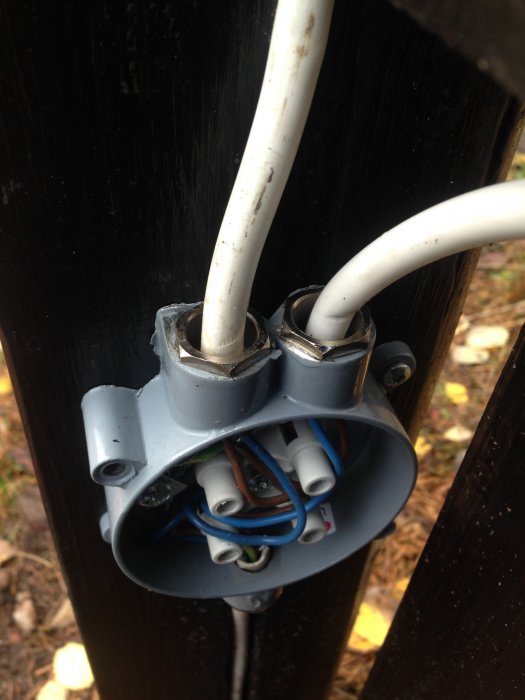Öppen kopplingsdosa med två elektriska kablar som inte ser vattentäta ut mot en svart bakgrund.